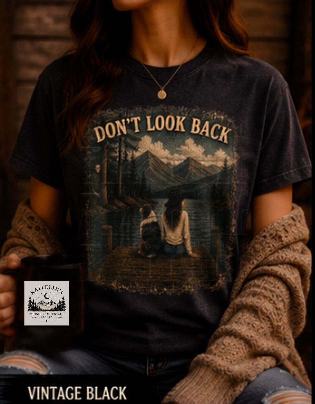 A person wearing a vintage black graphic T-shirt with a mountain lake scene and the text 'DON'T LOOK BACK' across the chest, styled with a brown knit cardigan and ripped jeans. A small brand sticker reading 'ASTROIC' is visible near the lower left.